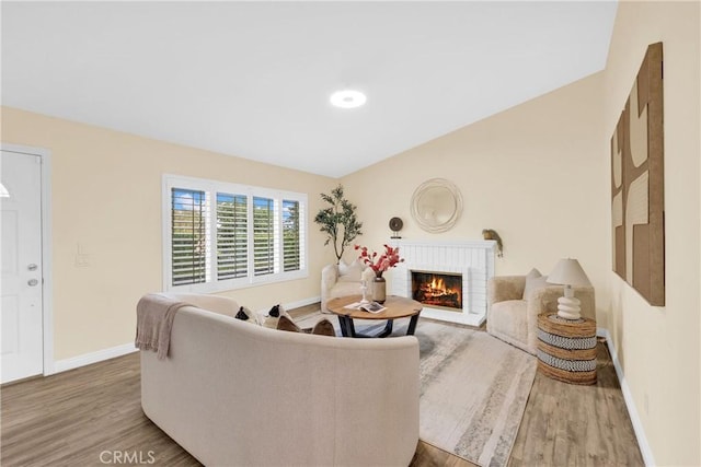 living room with hardwood / wood-style flooring and a brick fireplace