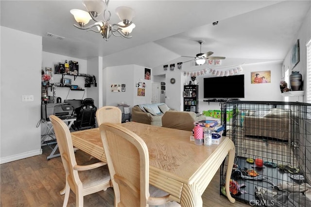 dining area with vaulted ceiling, ceiling fan with notable chandelier, and hardwood / wood-style floors