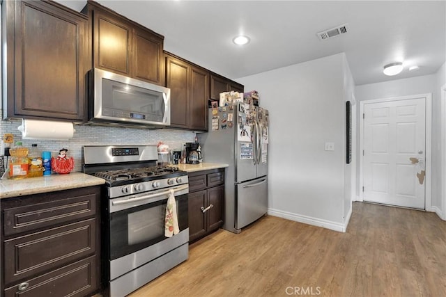 kitchen with dark brown cabinetry, backsplash, light hardwood / wood-style flooring, and appliances with stainless steel finishes