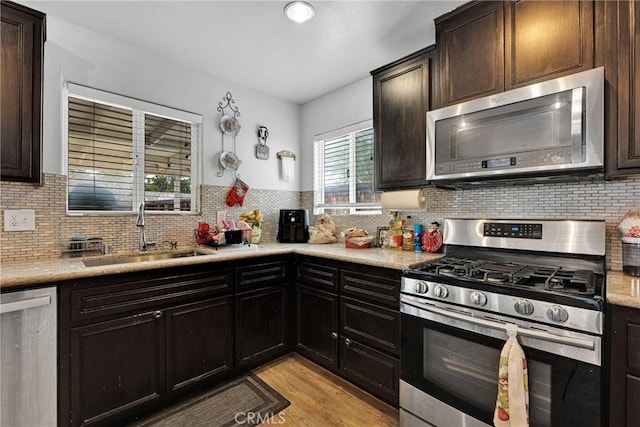 kitchen with stainless steel appliances, sink, dark brown cabinetry, and light wood-type flooring