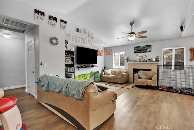 living room featuring a tiled fireplace, vaulted ceiling, hardwood / wood-style flooring, and ceiling fan