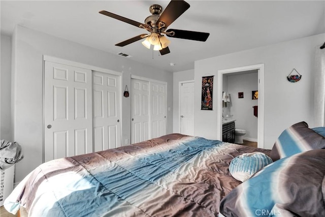 bedroom featuring connected bathroom, two closets, and ceiling fan