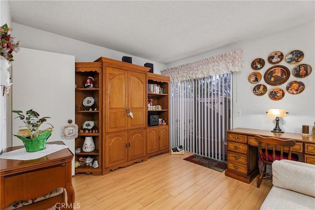 office area with light hardwood / wood-style floors and a textured ceiling