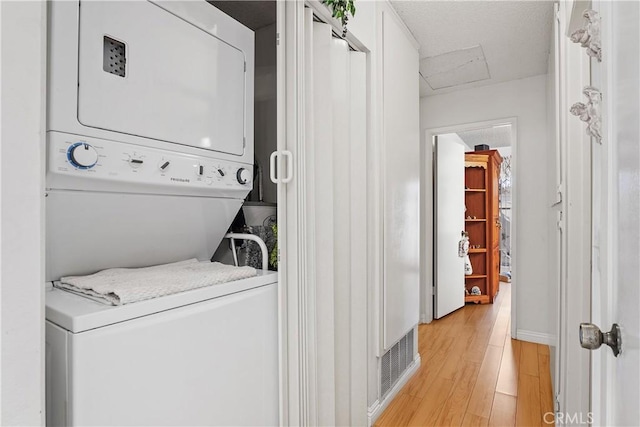 laundry room with stacked washing maching and dryer and light wood-type flooring