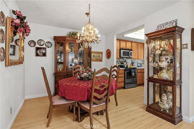 dining space featuring a chandelier, a textured ceiling, and light hardwood / wood-style floors