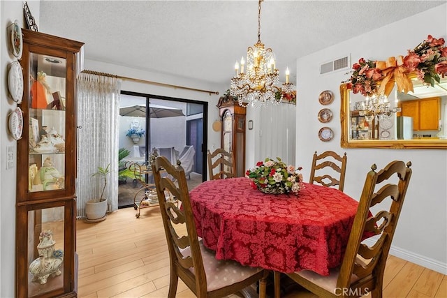 dining space with an inviting chandelier, light hardwood / wood-style flooring, and a textured ceiling