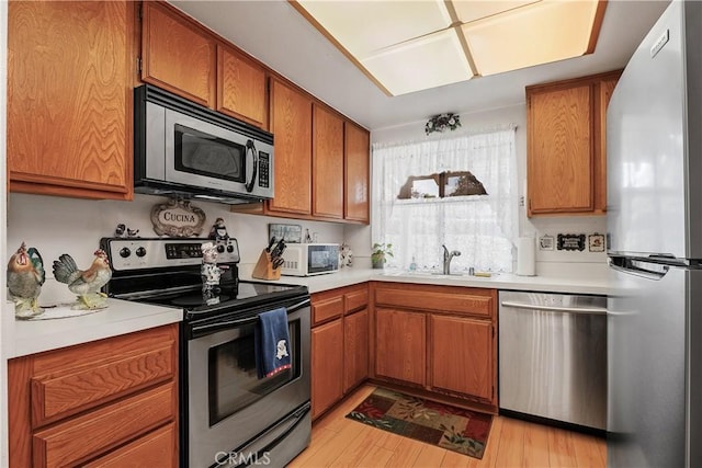 kitchen featuring stainless steel appliances, sink, and light hardwood / wood-style flooring