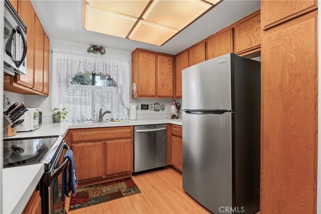 kitchen featuring appliances with stainless steel finishes, sink, and light wood-type flooring