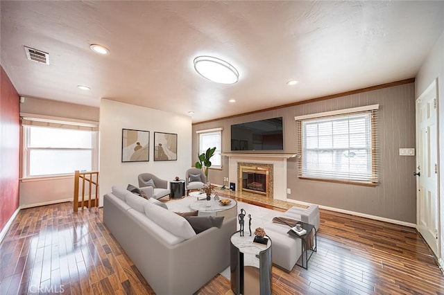 living room featuring crown molding, a high end fireplace, dark hardwood / wood-style floors, and plenty of natural light