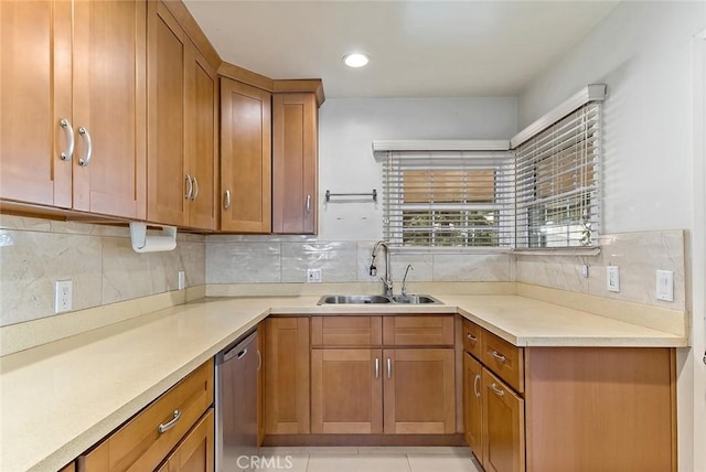 kitchen featuring stainless steel dishwasher, sink, decorative backsplash, and light tile patterned floors