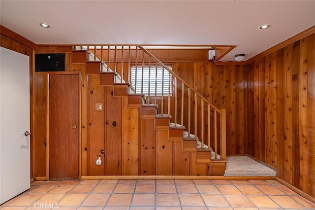 stairway with ornamental molding and wooden walls