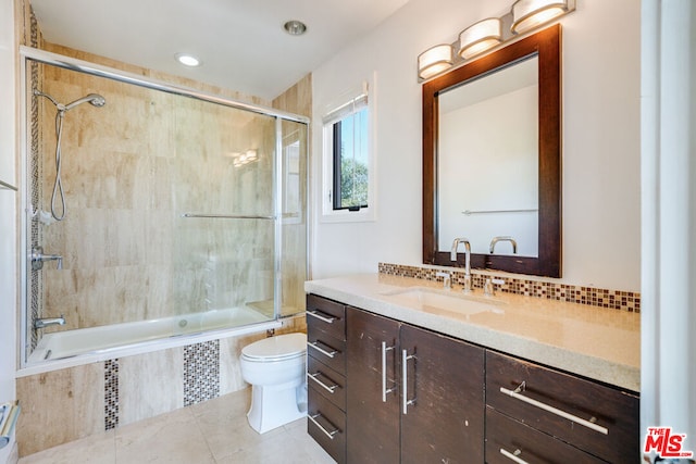 full bathroom with combined bath / shower with glass door, vanity, tasteful backsplash, tile patterned floors, and toilet