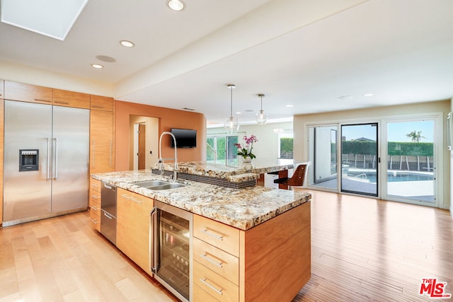 kitchen featuring pendant lighting, sink, wine cooler, a kitchen island with sink, and stainless steel built in fridge