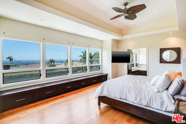 bedroom featuring a raised ceiling, ceiling fan, and light hardwood / wood-style floors