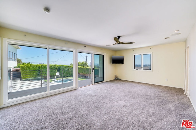 carpeted spare room featuring ceiling fan and a wealth of natural light