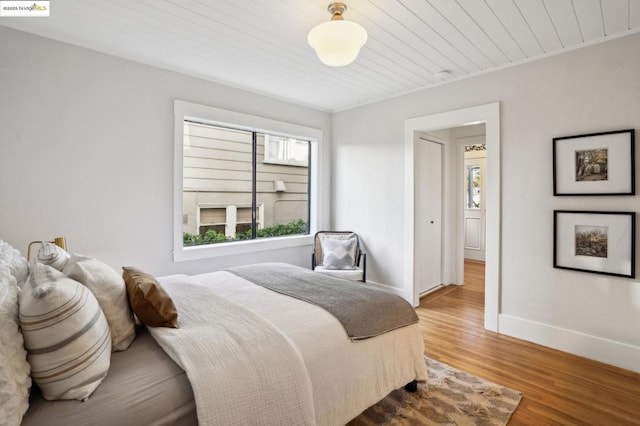 bedroom featuring multiple windows, wood-type flooring, and wood ceiling