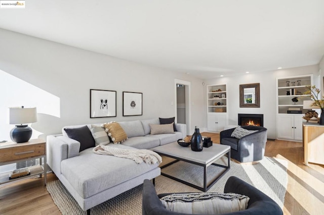 living room featuring built in features and light hardwood / wood-style flooring