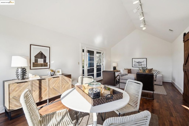 dining area featuring dark wood-type flooring, track lighting, french doors, vaulted ceiling, and a barn door