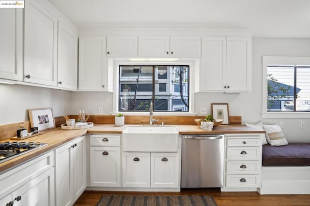 kitchen featuring butcher block countertops, sink, dark wood-type flooring, appliances with stainless steel finishes, and white cabinetry