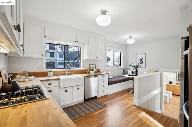 kitchen featuring stainless steel appliances, sink, light hardwood / wood-style flooring, and white cabinets