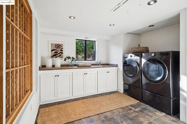 clothes washing area with cabinets, washer and clothes dryer, and sink