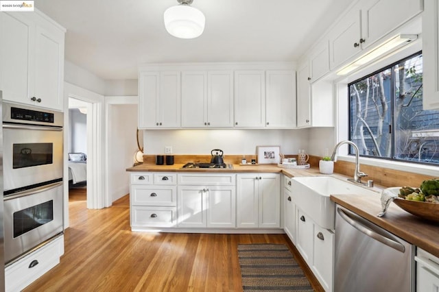 kitchen featuring wood counters, sink, stainless steel appliances, and white cabinets