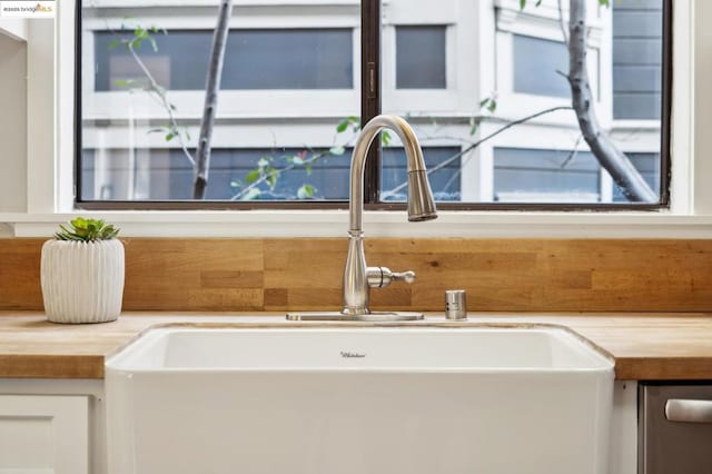 details with butcher block counters, sink, and white cabinets