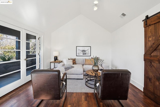 living room featuring dark hardwood / wood-style floors, a barn door, vaulted ceiling, and french doors