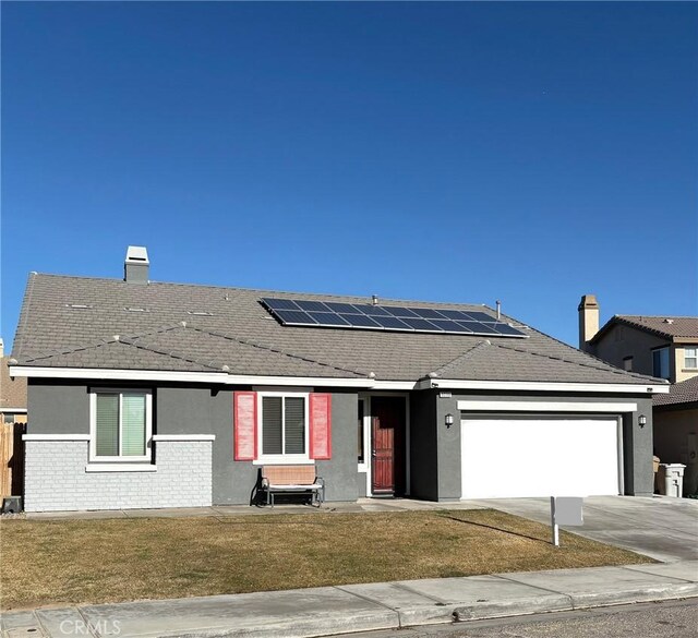 view of front of house featuring a garage, a front yard, and solar panels