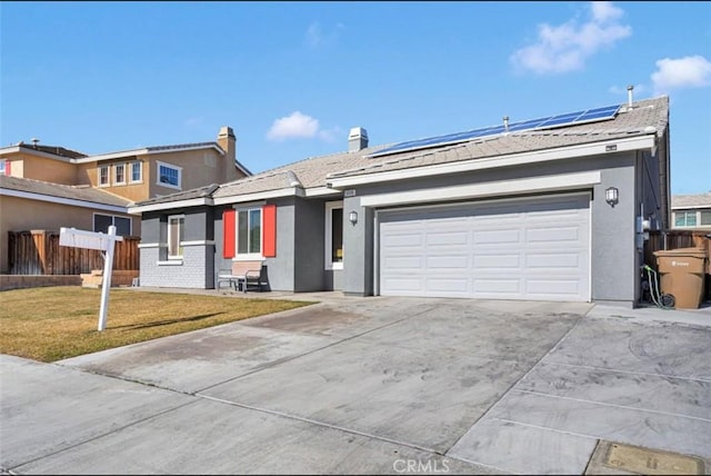 single story home featuring a garage, a front lawn, and solar panels