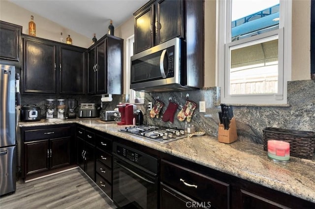 kitchen with tasteful backsplash, light stone countertops, hardwood / wood-style flooring, and stainless steel appliances