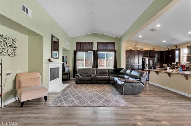 living room with vaulted ceiling and light hardwood / wood-style flooring