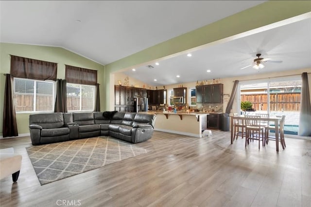 living room featuring vaulted ceiling, ceiling fan, and light hardwood / wood-style floors