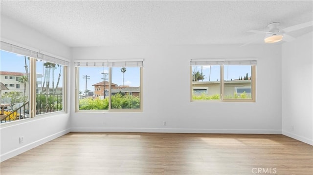 unfurnished room featuring plenty of natural light, light hardwood / wood-style floors, and a textured ceiling