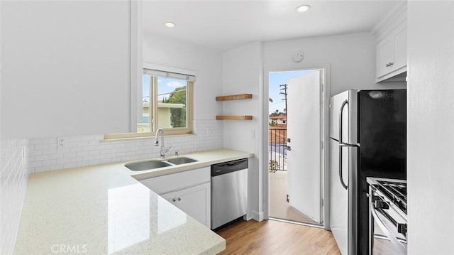 kitchen featuring sink, appliances with stainless steel finishes, backsplash, light stone counters, and white cabinets