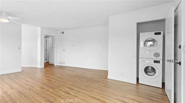 washroom featuring stacked washing maching and dryer and light hardwood / wood-style flooring