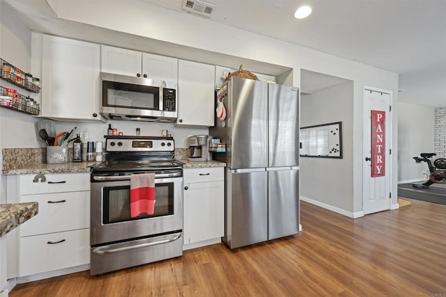 kitchen with light stone countertops, light hardwood / wood-style flooring, stainless steel appliances, and white cabinets