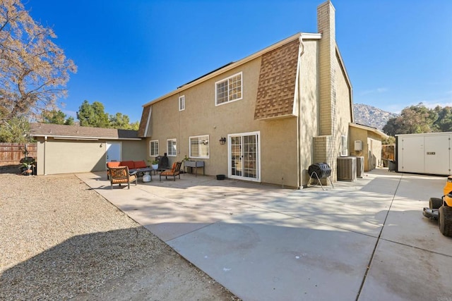 rear view of property featuring central AC unit, an outdoor living space, a mountain view, and a patio