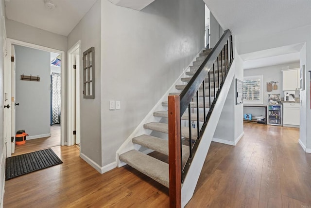 stairway featuring wine cooler and hardwood / wood-style flooring