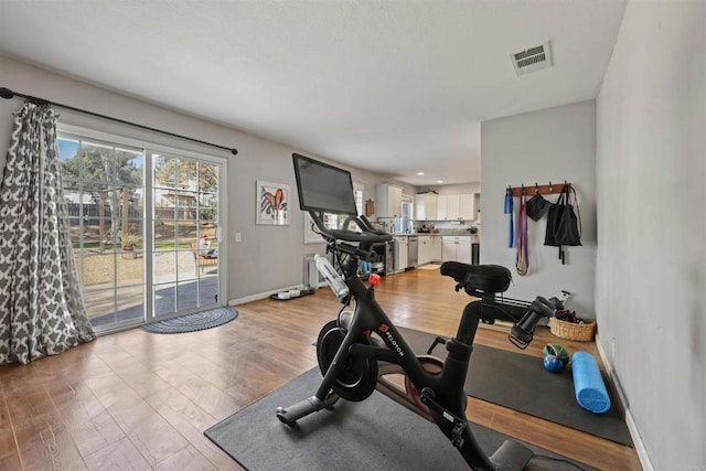 exercise area featuring baseboards, visible vents, and light wood-type flooring