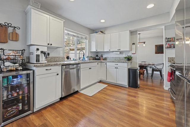 kitchen with a sink, stainless steel dishwasher, beverage cooler, and light wood finished floors