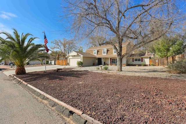 view of front of property with an attached garage, concrete driveway, and fence