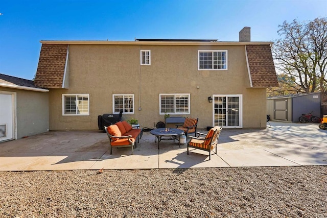 back of house with stucco siding, a patio area, a chimney, and a shingled roof