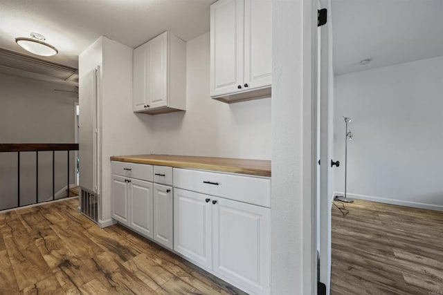 kitchen featuring white cabinets, wood finished floors, and baseboards