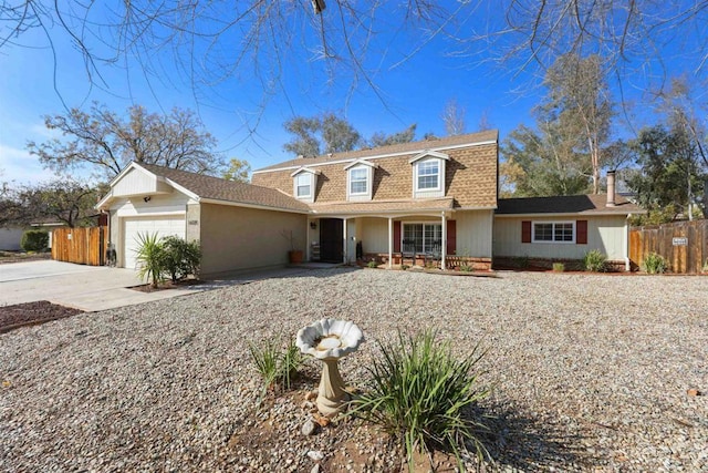 colonial inspired home with fence, roof with shingles, mansard roof, a garage, and driveway