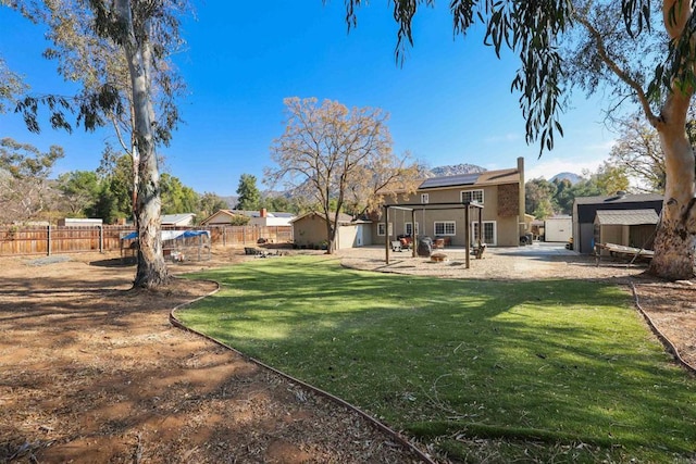 view of yard with a storage shed, a patio, an outbuilding, and a fenced backyard