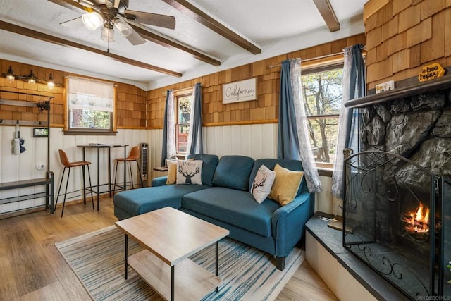 living room with beamed ceiling, light hardwood / wood-style floors, and wood walls