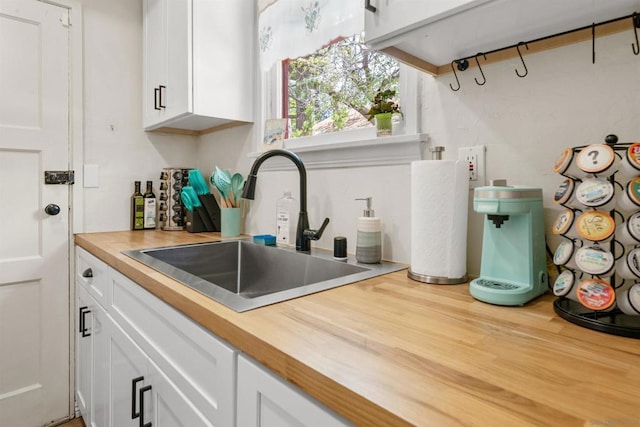 kitchen featuring white cabinetry, sink, and butcher block counters