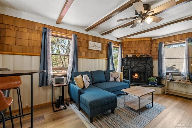 living room with a fireplace, beam ceiling, light hardwood / wood-style flooring, and ceiling fan