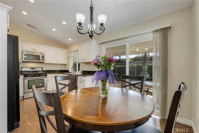 dining space with lofted ceiling, sink, a notable chandelier, and light hardwood / wood-style flooring